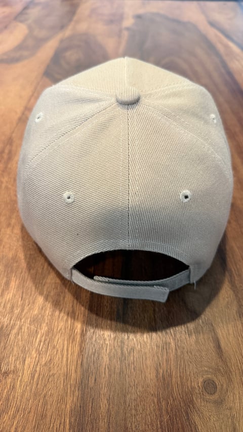 White baseball cap with rear snapback closure viewed from above on a wooden surface